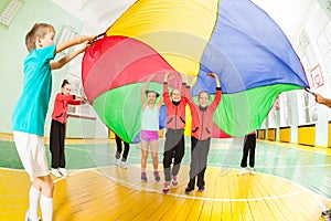 Children playing parachute games in sports hall