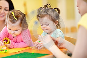Children playing with plasticine at kindergarten or playschool photo