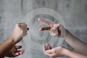 Children playing rock paper scissors. Gray background with copy space. photo