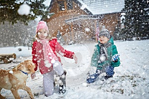 Children playing on snow with dog in winter holiday