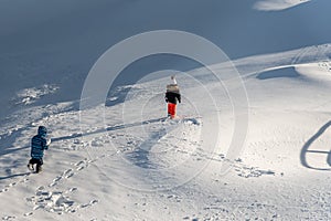 Children playing in snow. One Asian boy and girl in ski-wear hiking in winter