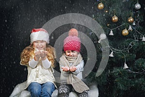 Children playing with snowflakes on dark background near the Christmas tree