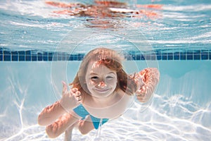 Children playing in swimming pool. Young boy swim and dive underwater. Under water portrait in swim pool. Child boy