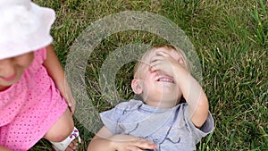 Children playing tickle on the grass in the park.