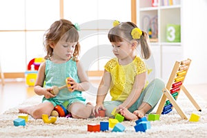 Children playing together with building blocks. Educational toys for preschool and kindergarten kids. Little girls build