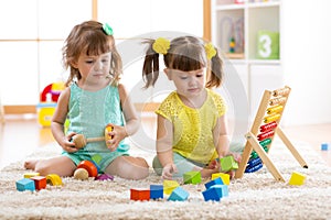 Children playing together with building blocks. Educational toys for preschool and kindergarten kids. Little girls build toys at h