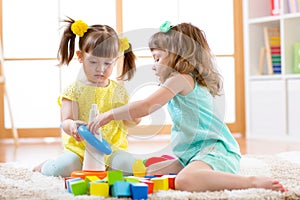 Children playing together. Toddler kid and baby play with blocks. Educational toys for preschool and kindergarten child