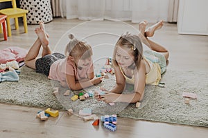 Children playing with toy building blocks on the floor at home or kindergarten