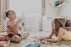 Children playing with toy building blocks on the floor at home or kindergarten