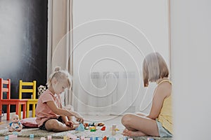 Children playing with toy building blocks on the floor at home or kindergarten