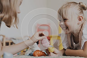 Children playing with toy play tea set on the floor at home or kindergarten