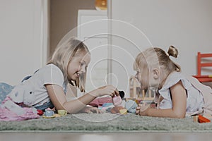 Children playing with toy play tea set on the floor at home or kindergarten