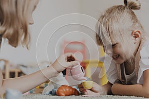 Children playing with toy play tea set on the floor at home or kindergarten