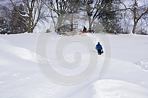Children playing, walking up along snowy hill with sled on winter day. Outdoor fun for family. Winter activity.