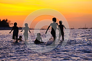 Children playing in water at sunset