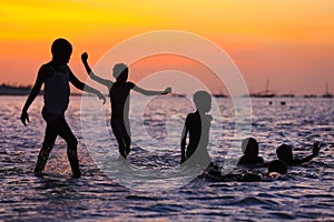 Children playing in the water at sunset