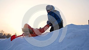 Children playing in winter on a snowy mountain against the sky