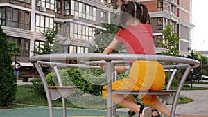 Children with pleasure and laughter are spinning on a carousel in the courtyard of a modern neighborhood.