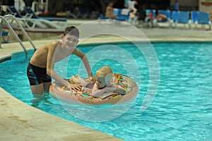 Children at pool, happiness and joy. Two brothers having fun swimming ring