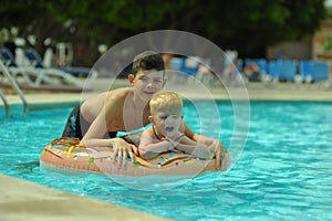 Children at pool, happiness and joy. Two brothers having fun swimming ring