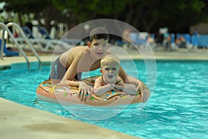 Children at pool, happiness and joy. Two brothers having fun swimming ring