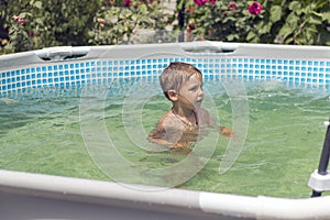 Children in the pool near the house swim and indulge. Two brothers are swimming in a frame pool. Blue water and bright swimming