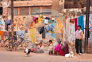 Children of poor family play outdoor near the village house with drying clothes