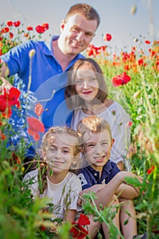 Children among poppy field with parents out of focus