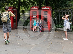 Children pose for father by traditional red telephone booths, Lo
