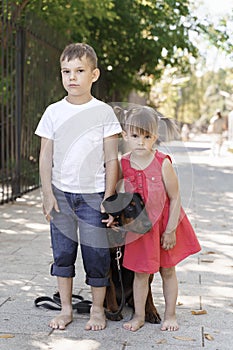 Children posing with beautiful doberman puppy in the park