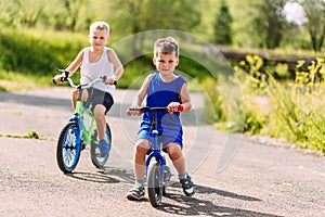 Children preschoolers ride bikes in the summer in the Park on the pavement