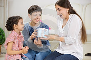 Children presenting a gift to mother photo