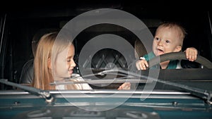 Children pretend driving car sitting on front vehicle seats