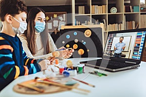 Children with protective mask presenting there science home project - the planets of our solar system. Distance learning