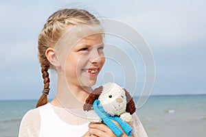 Children psychology. The little beautiful girl embraces an amusing dog - toy. Favorite soft toy.