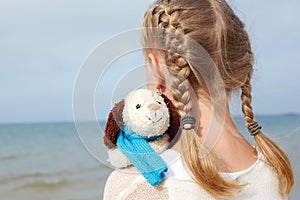 Children psychology. The little beautiful girl embraces an amusing dog - toy. Favorite soft toy.