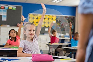 Children raising hands in classroom