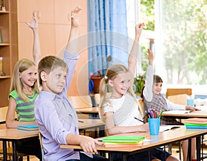 Children raising hands knowing the answer to the question