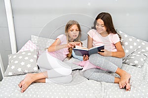 Children read book in bed. Family tradition. Girls best friends read fairy tale before sleep. Best books for kids