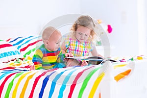Children reading a book in bed