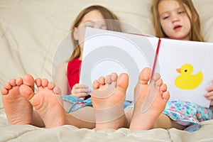 Children reading a book in bed