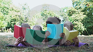 Children reading books, lying mat in park, book lovers club, education concept