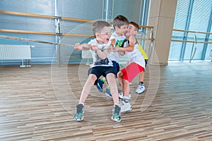 Children and recreation, group of happy multiethnic school kids playing tug-of-war with rope in gym