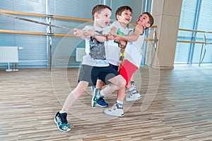 Children and recreation, group of happy multiethnic school kids playing tug-of-war with rope in gym