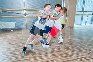 Children and recreation, group of happy multiethnic school kids playing tug-of-war with rope in gym