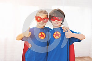 Children in the red and blue suits of superheroes. They in masks. Kids posing in bright room.