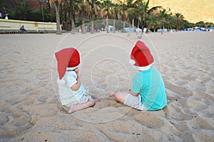 Children in red santa hats have fun on ocean sand beach