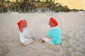 Children in red santa hats have fun on ocean sand beach