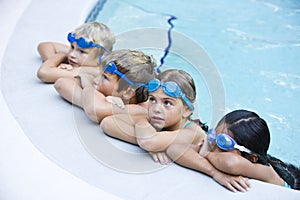 Children resting, hanging on side of swimming pool