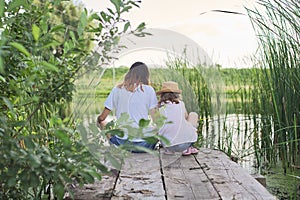 Children resting near the water on sunny summer day, back view